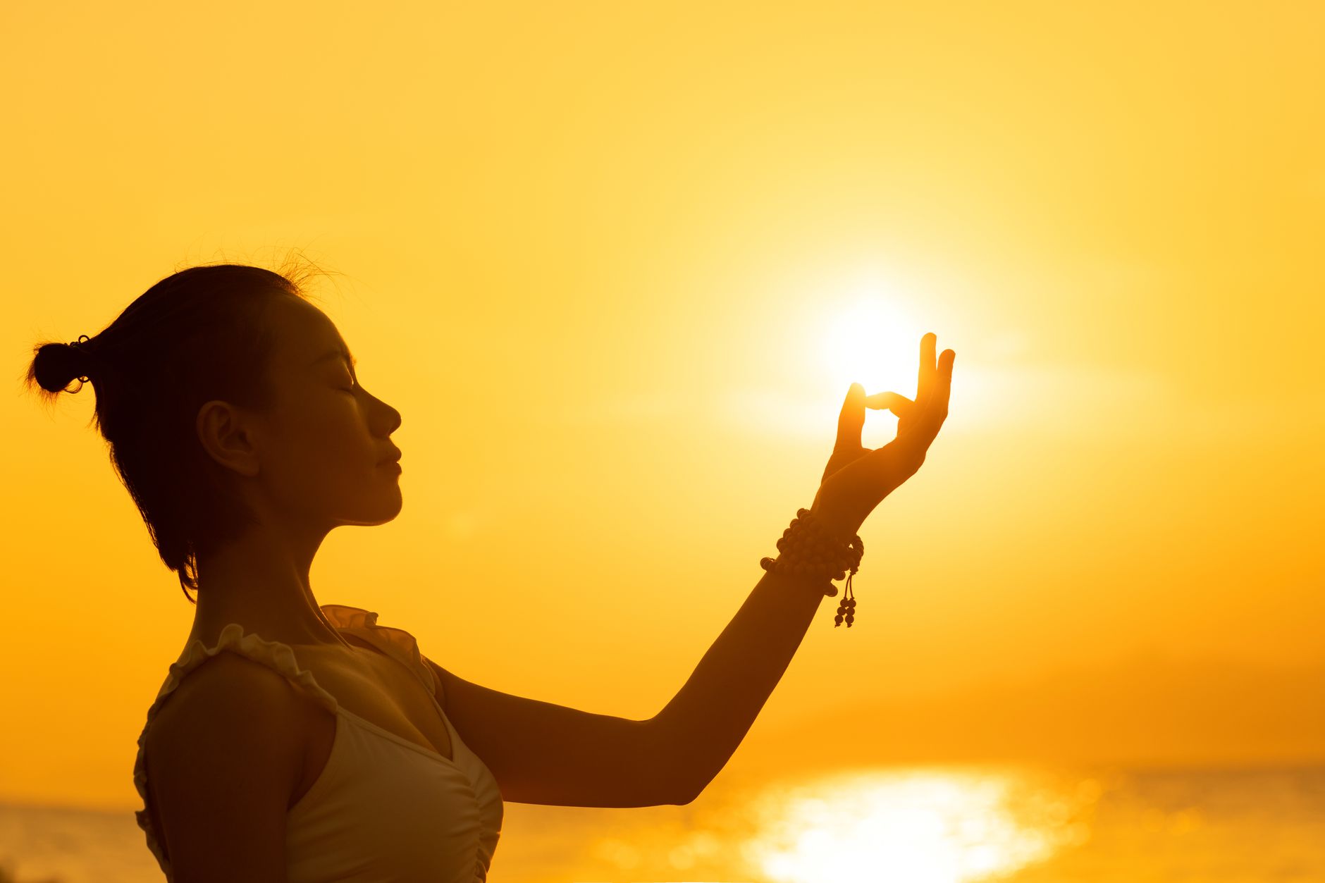 woman meditating in front of setting sun